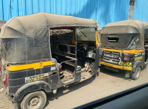 Two autorickshaws parked beside a street